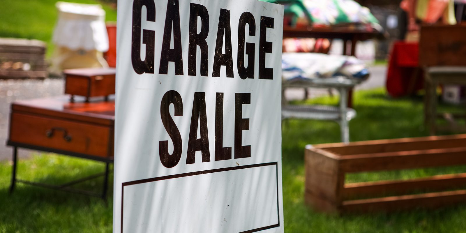 Garage sale sign on the shady lawn of a suburban home, shallow f